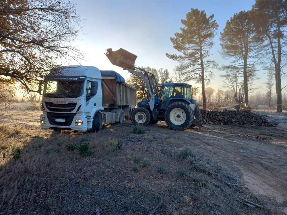 Un camión está siendo remolcado por un tractor en un camino de tierra.