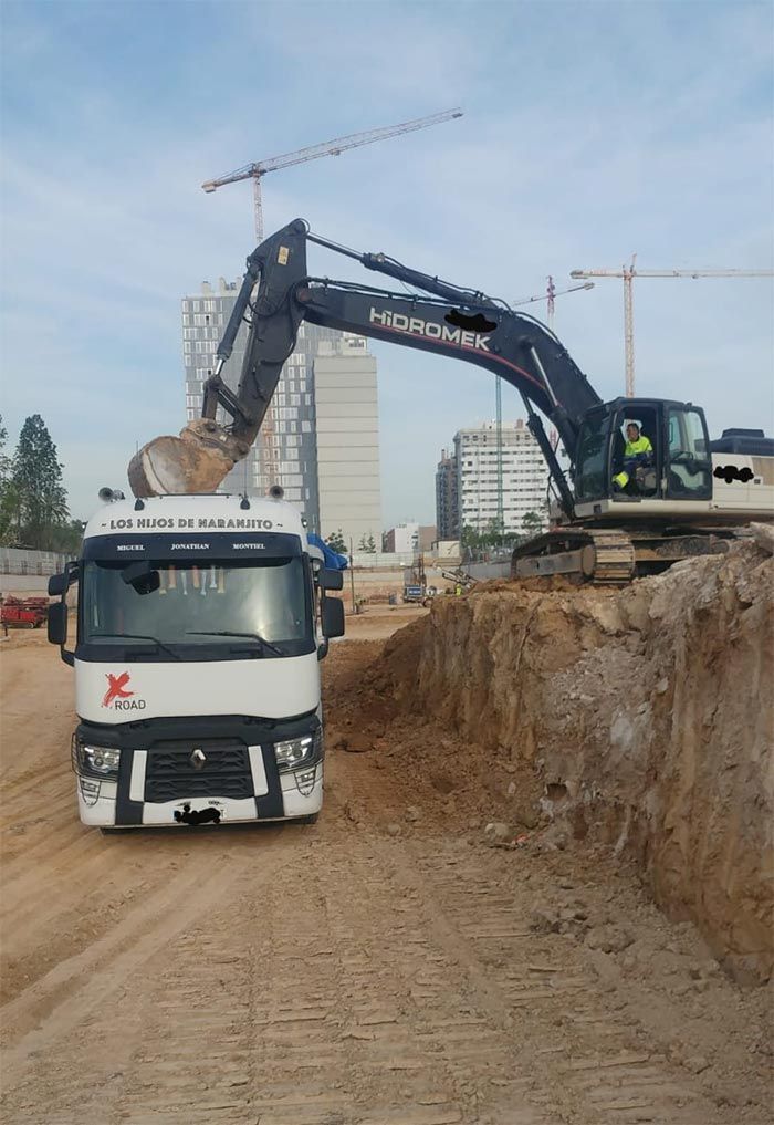 Un camión está siendo cargado con tierra por una excavadora grande.