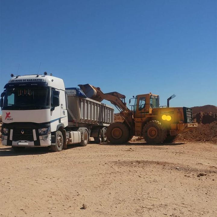 Un camión volquete está siendo cargado con tierra por una excavadora