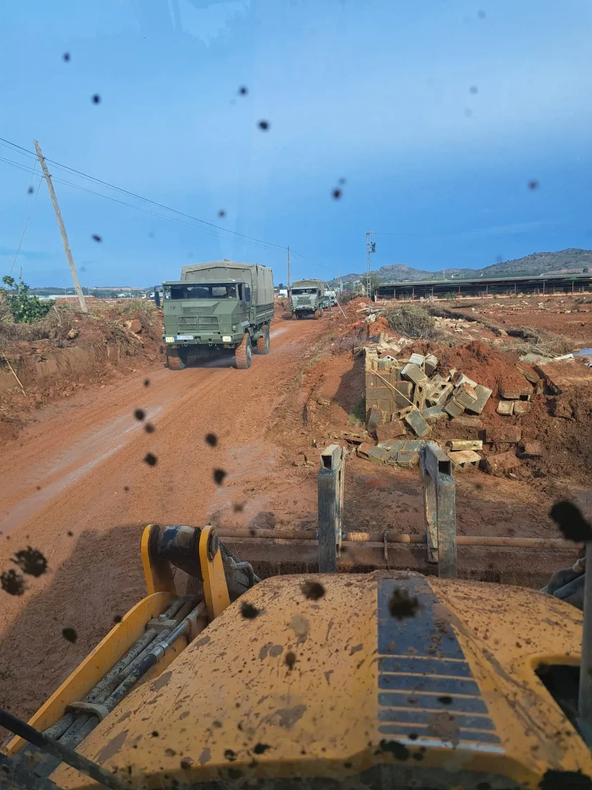 Un camión circula por un camino de tierra al lado de una excavadora.