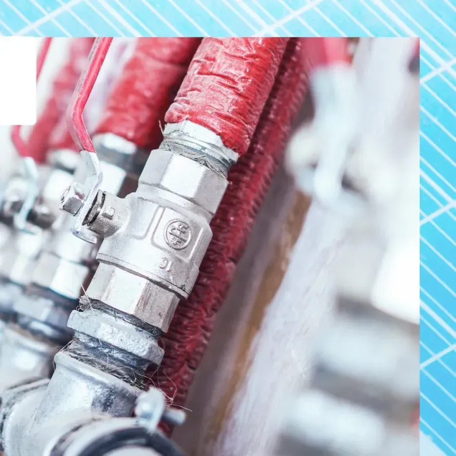 Sistema de plomería con tuberías aisladas en rojo y válvulas plateadas.