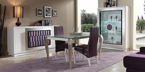 Un comedor con una mesa de cristal y sillas moradas.