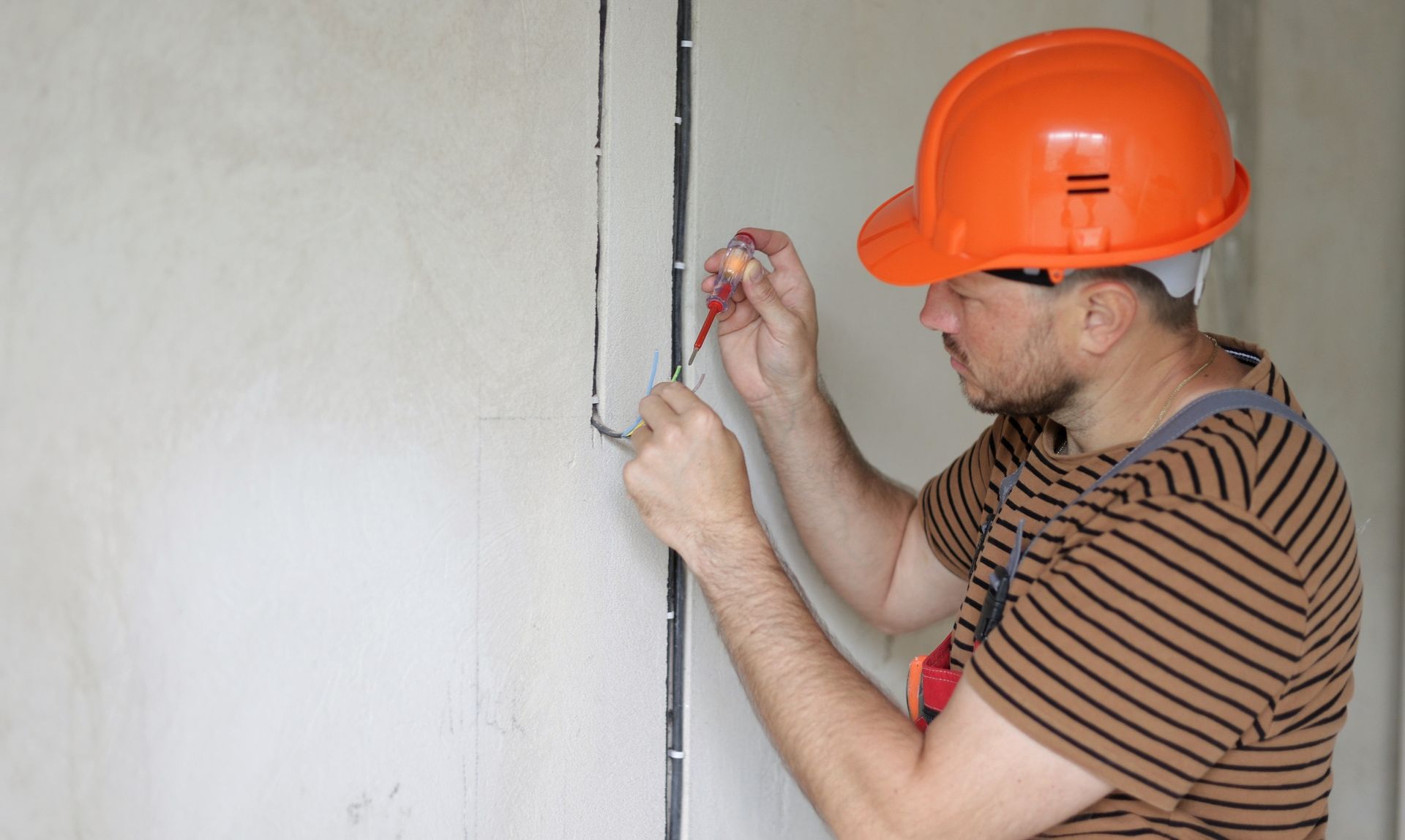 Un électricien posant des fils électriques dans une maison.