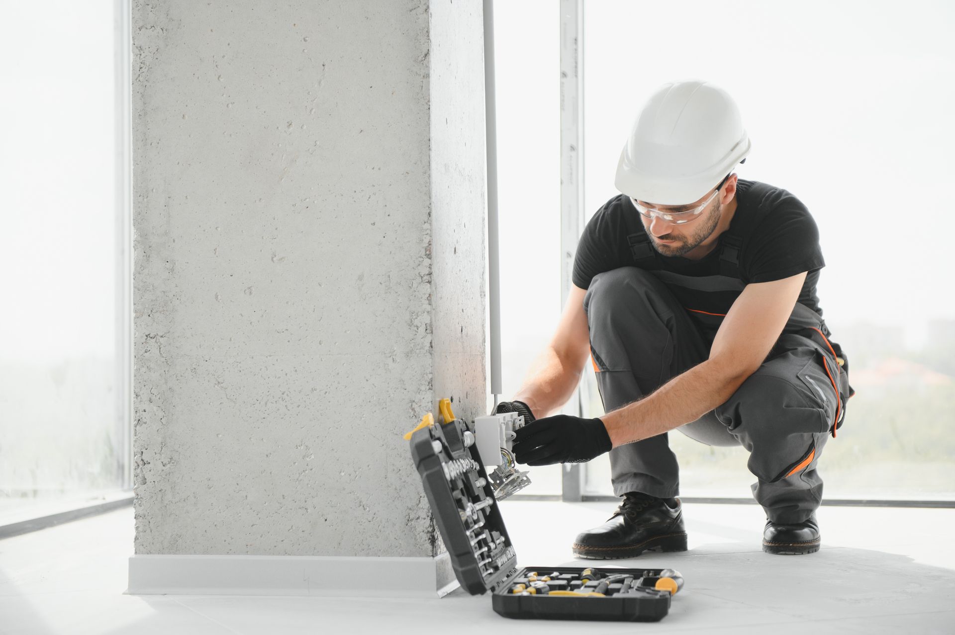 Homme installant des fils électriques dans un mur d'une maison.