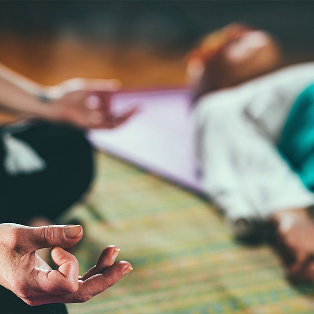 Una mujer está haciendo una pose de yoga en una colchoneta azul.