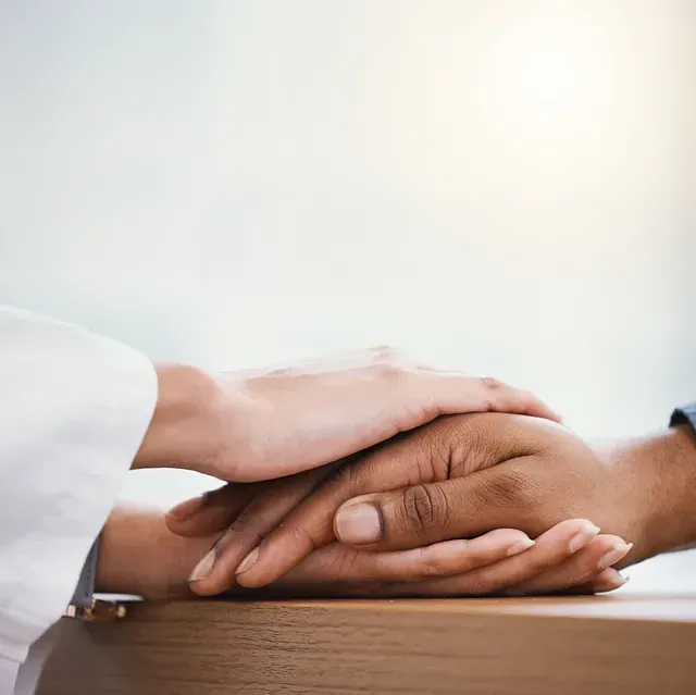 Una mujer sostiene la mano de un hombre sobre una mesa.