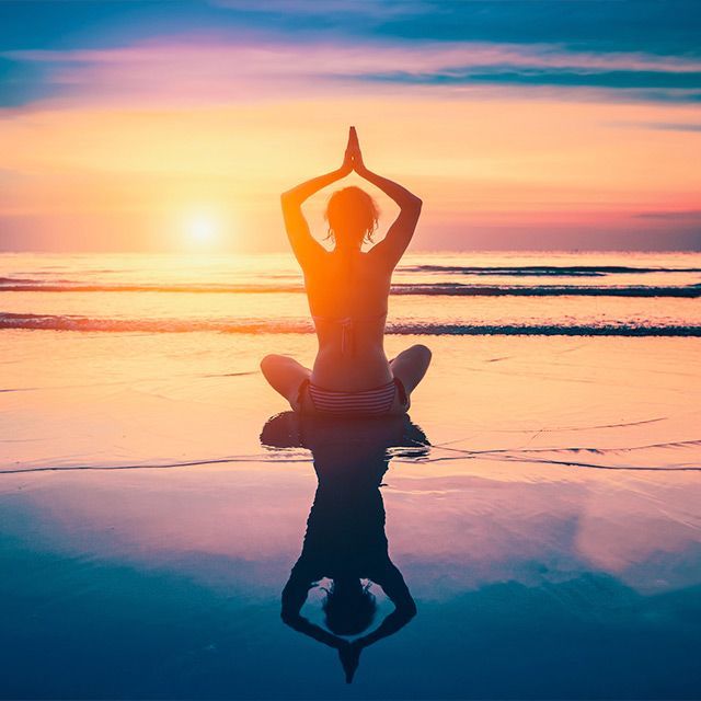 Una mujer está ayudando a otra mujer a hacer una pose de yoga.