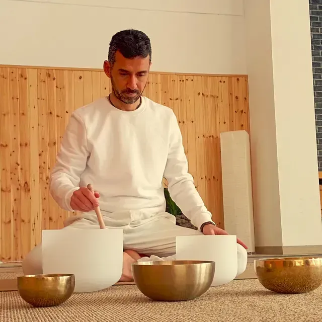 Un hombre con una camisa blanca está sentado en el suelo jugando a los bolos.