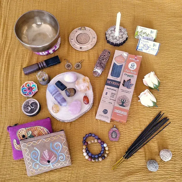 Una mesa cubierta con una variedad de artículos que incluyen varillas de incienso y un cuenco cantor.
