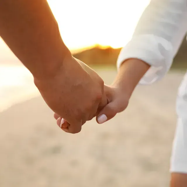 Un hombre y una mujer se toman de la mano en la playa.