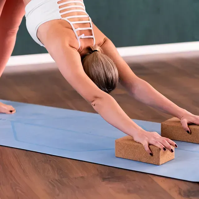 Una mujer está haciendo una pose de yoga en una colchoneta azul.