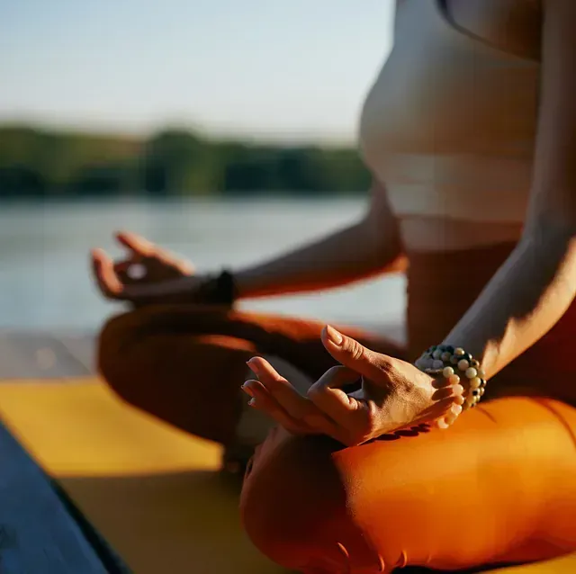 Una mujer está sentada en posición de loto sobre una estera de yoga.