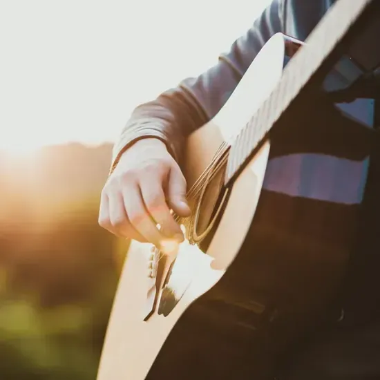 Un primer plano de una persona tocando una guitarra acústica.