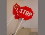 Señal de STOP roja en un poste blanco apoyado contra una pared en el interior de una vivienda.