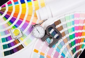 Muestras de color con rueda cromática, cronómetro y cinta métrica sobre un fondo blanco.