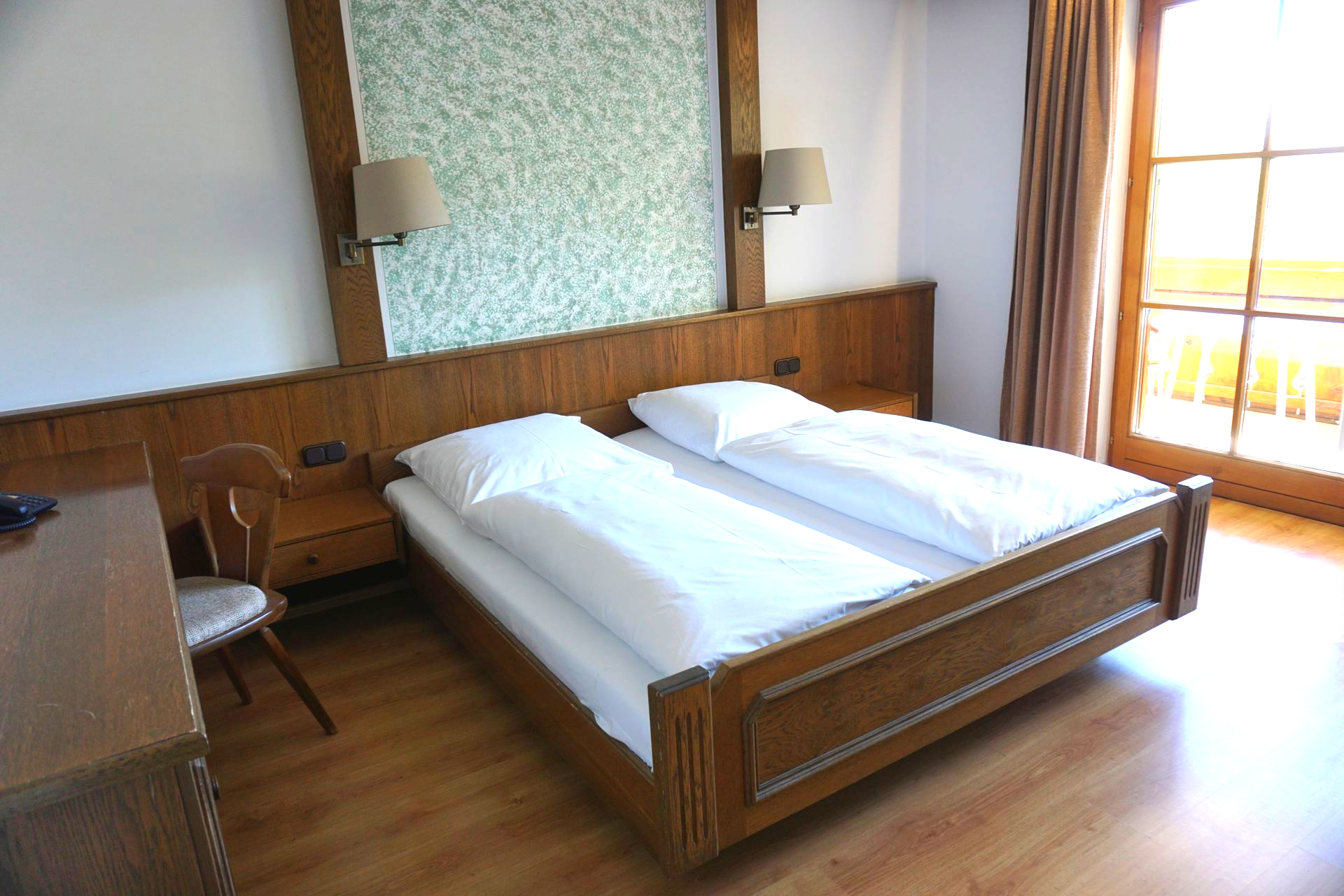 Gemütliches Schlafzimmer mit Holzbett, Balkonzugang und heller Einrichtung.
