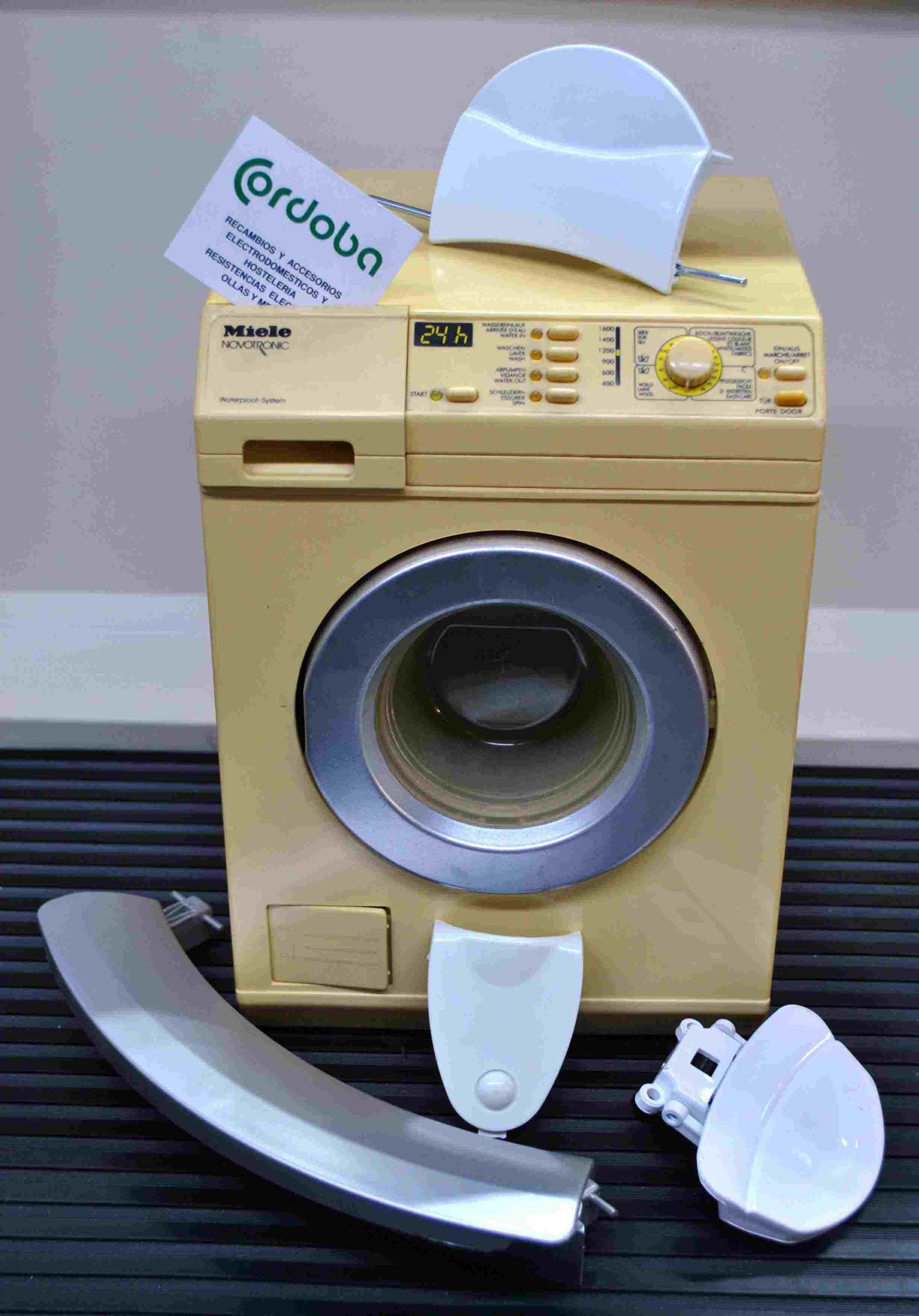 Una lavadora de juguete está sobre una mesa al lado de un trozo de metal.