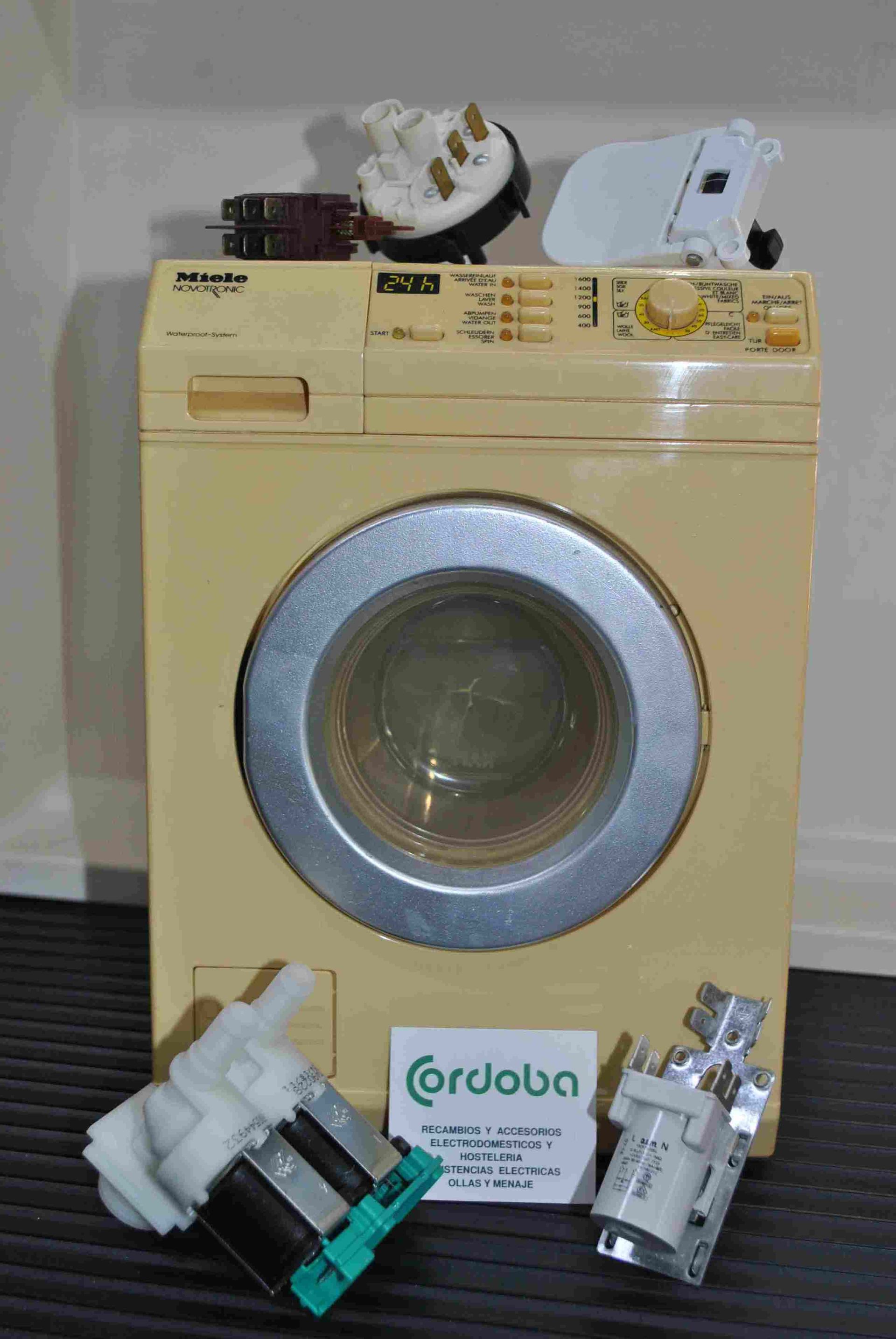 Una lavadora amarilla está sobre una mesa al lado de algunas piezas.