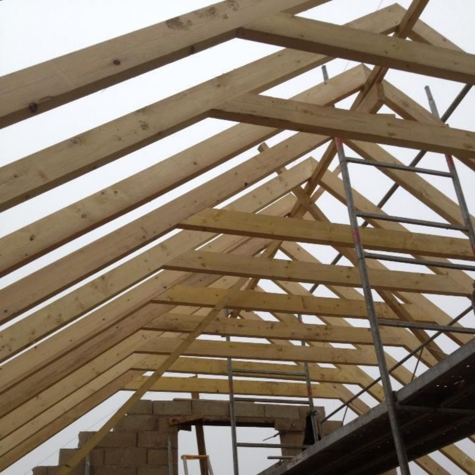 Charpente de toit en bois en construction, échafaudages visibles.