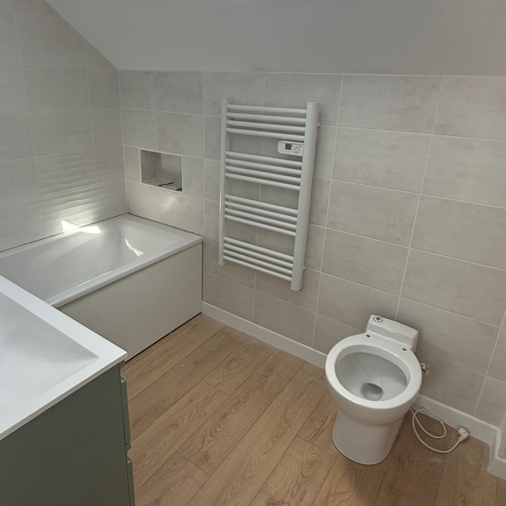 Salle de bains avec baignoire, toilettes et sèche-serviettes.