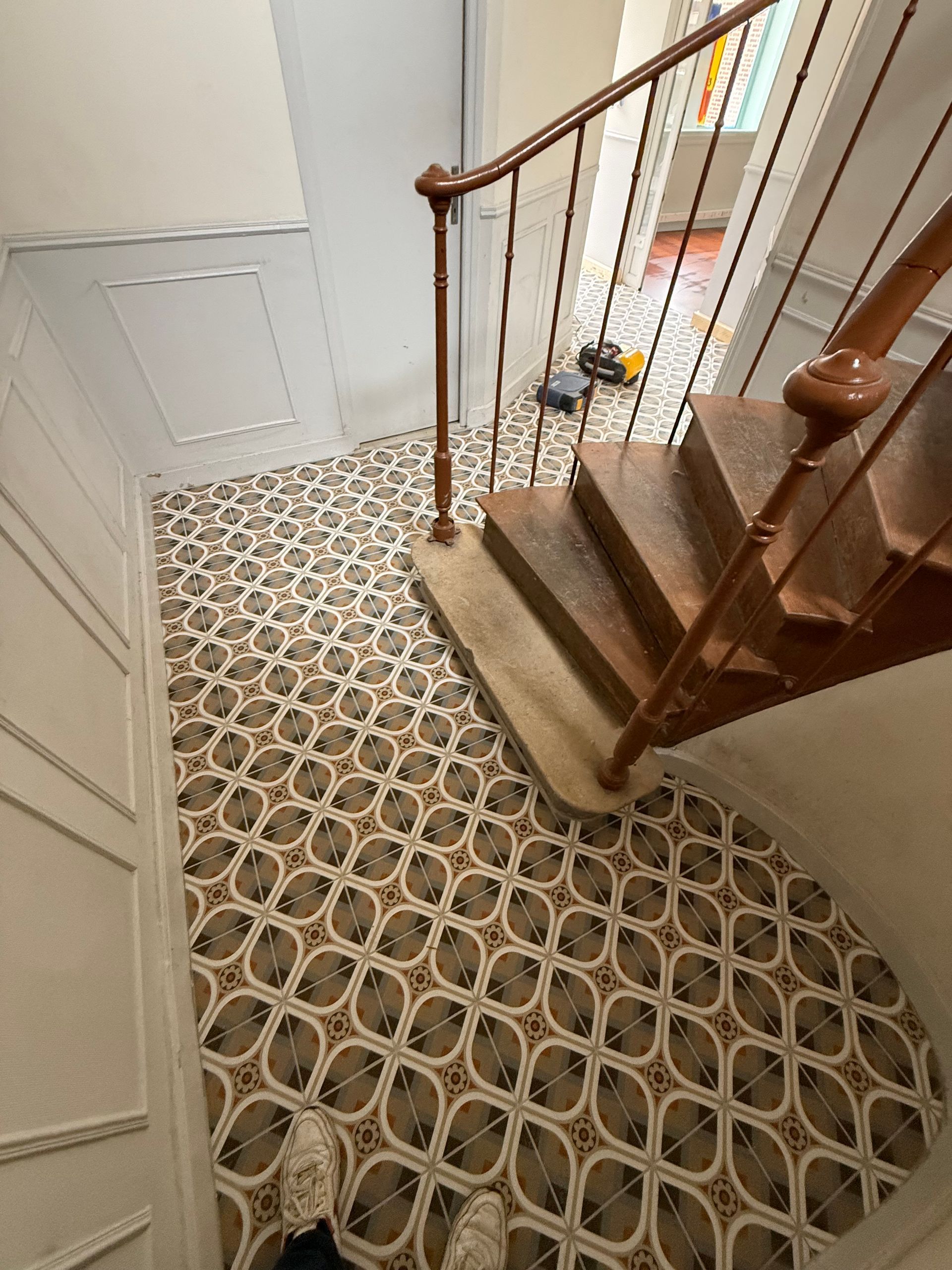 Cage d'escalier avec carrelage à motifs.