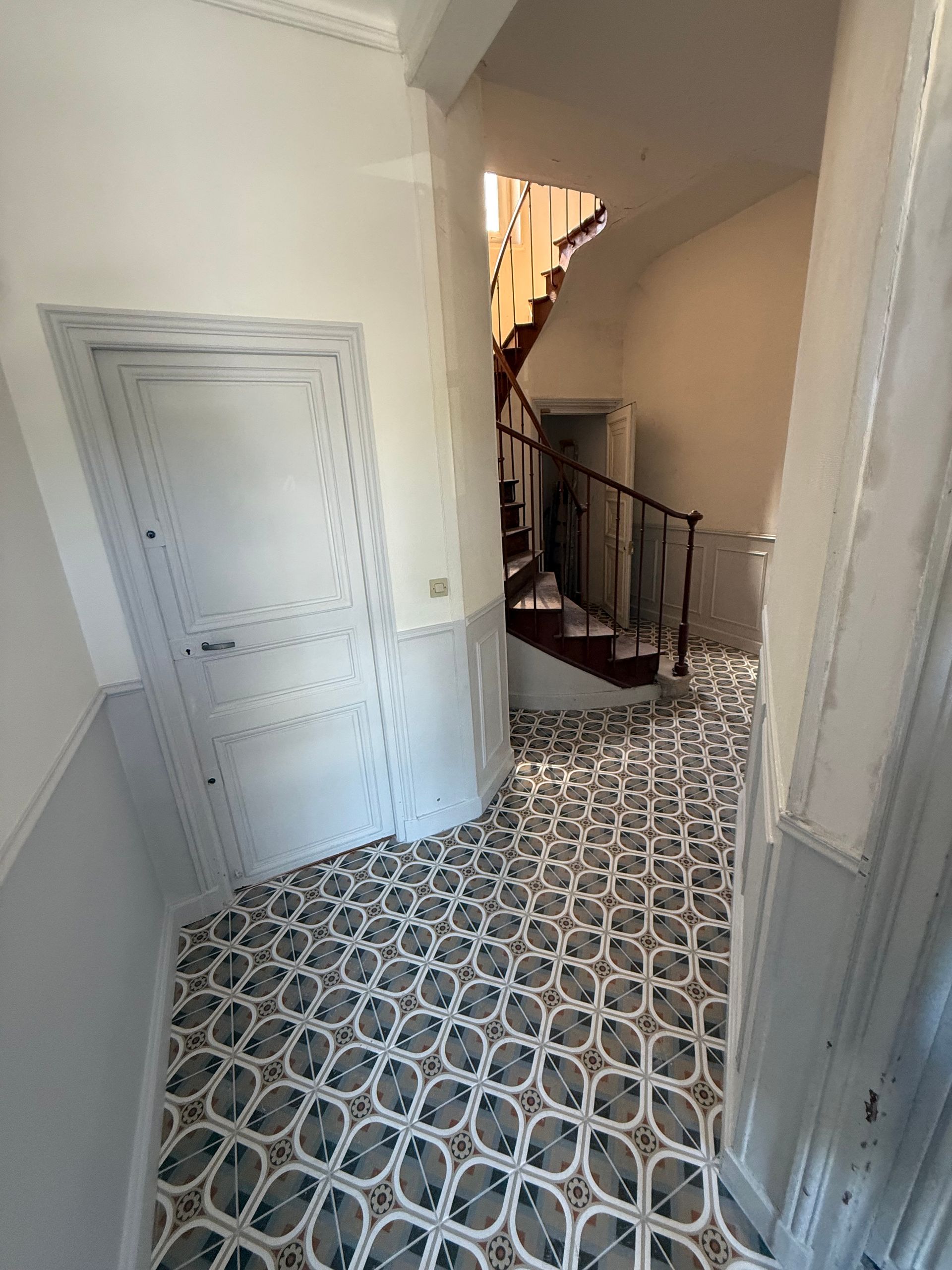 Couloir avec sol carrelé à motifs.