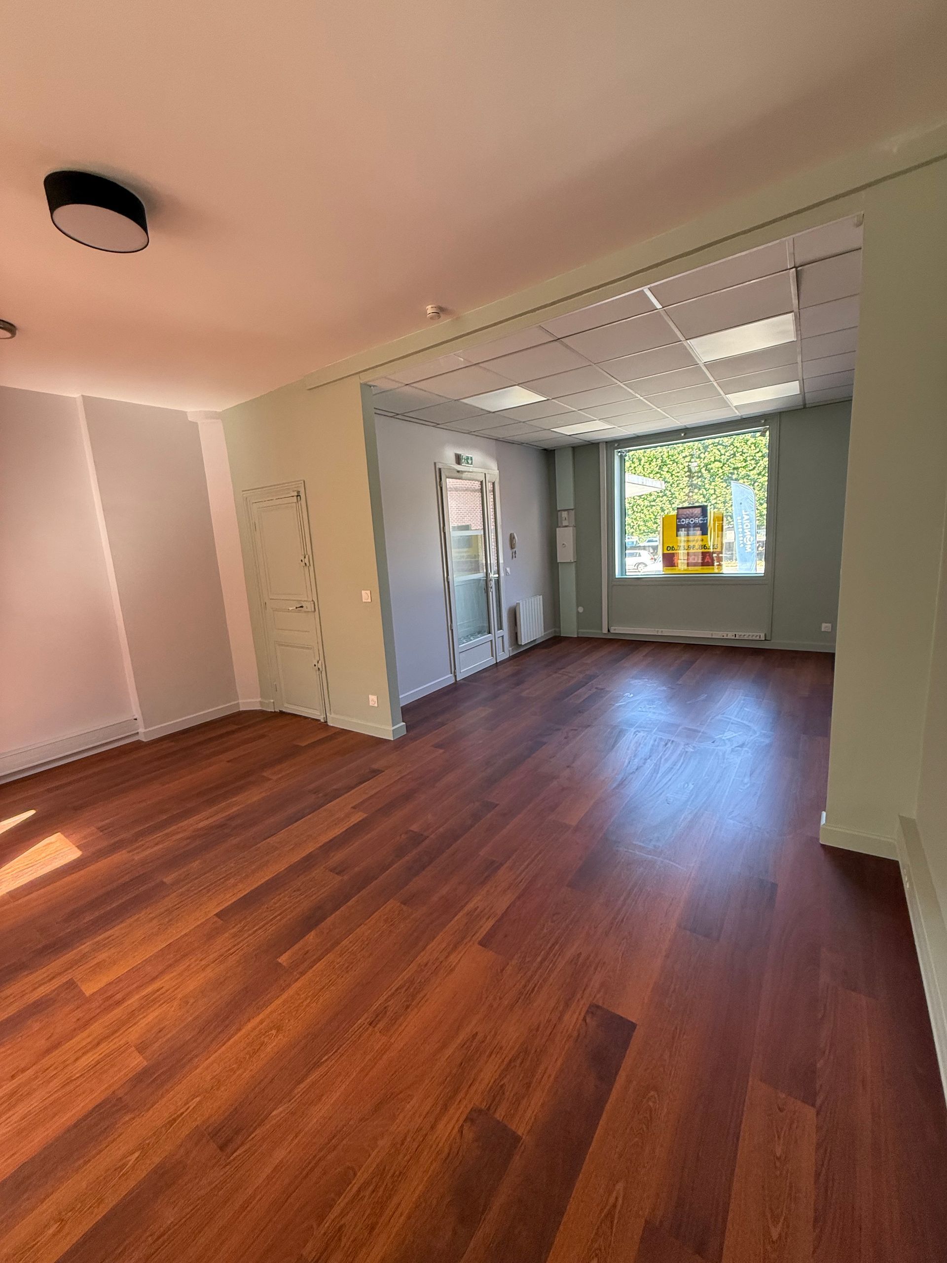 Pièce vide avec parquet et murs verts.