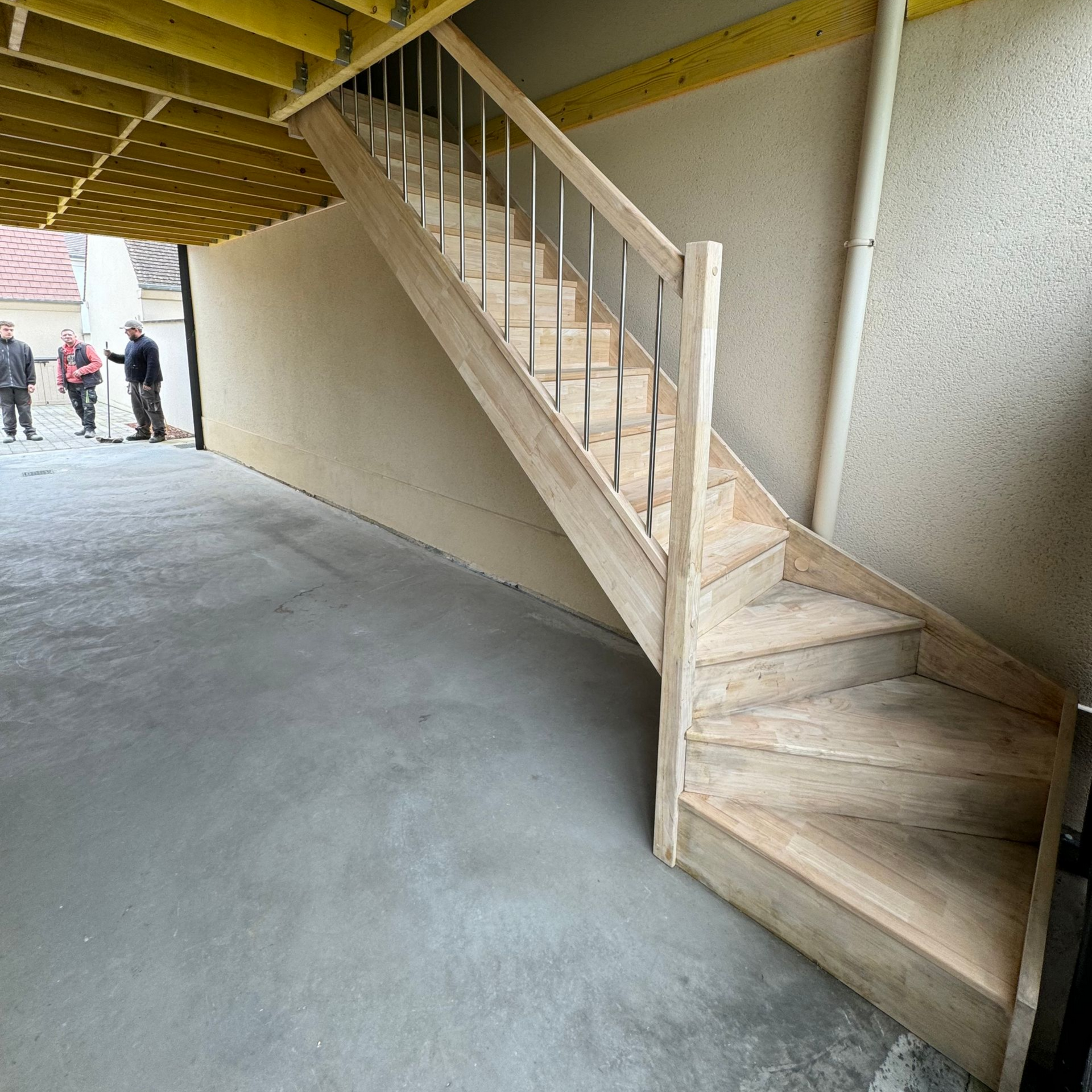 Escalier en bois avec rampes métalliques dans un espace en béton.
