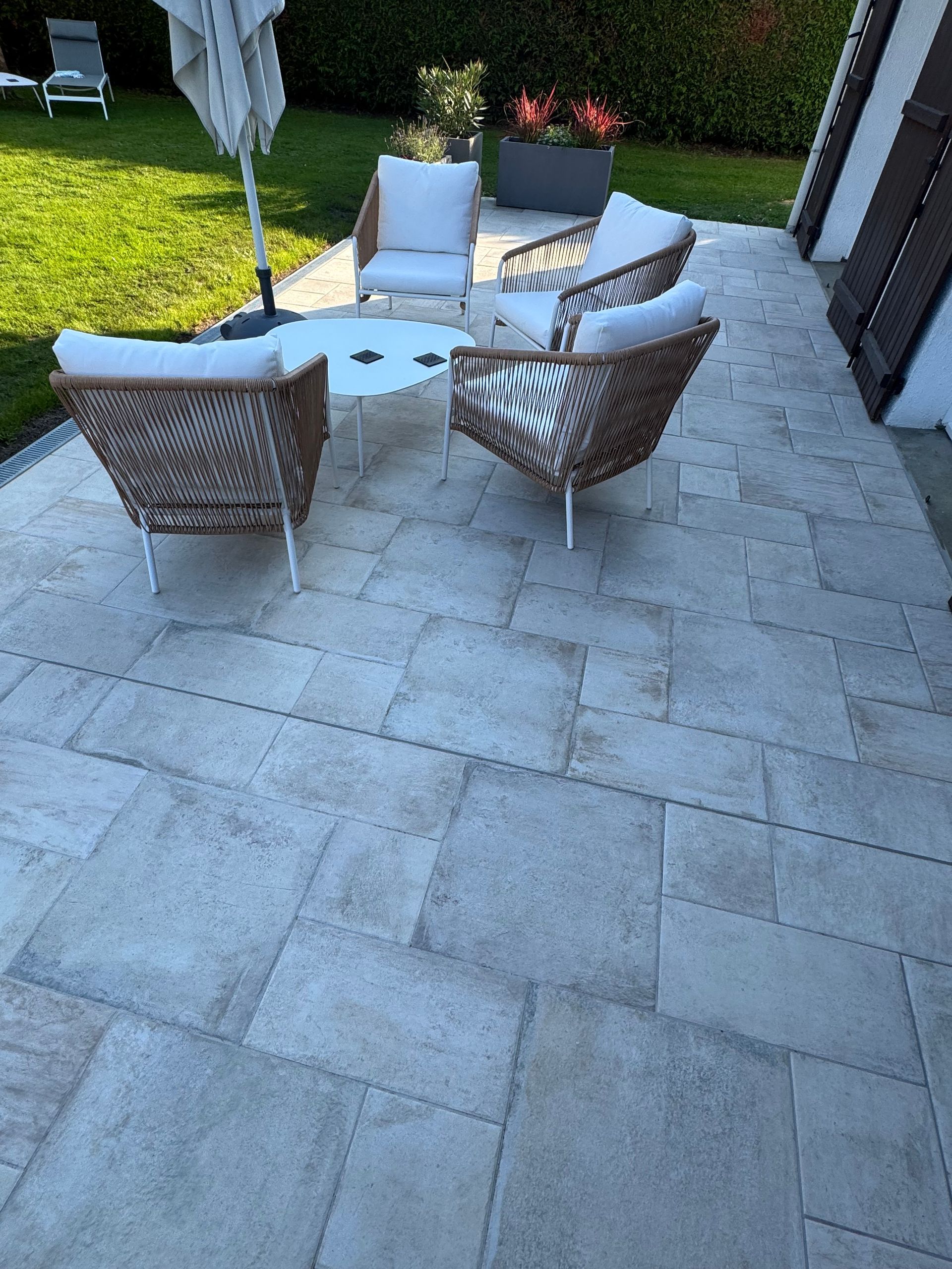 Terrasse avec quatre chaises en osier autour d'une petite table.