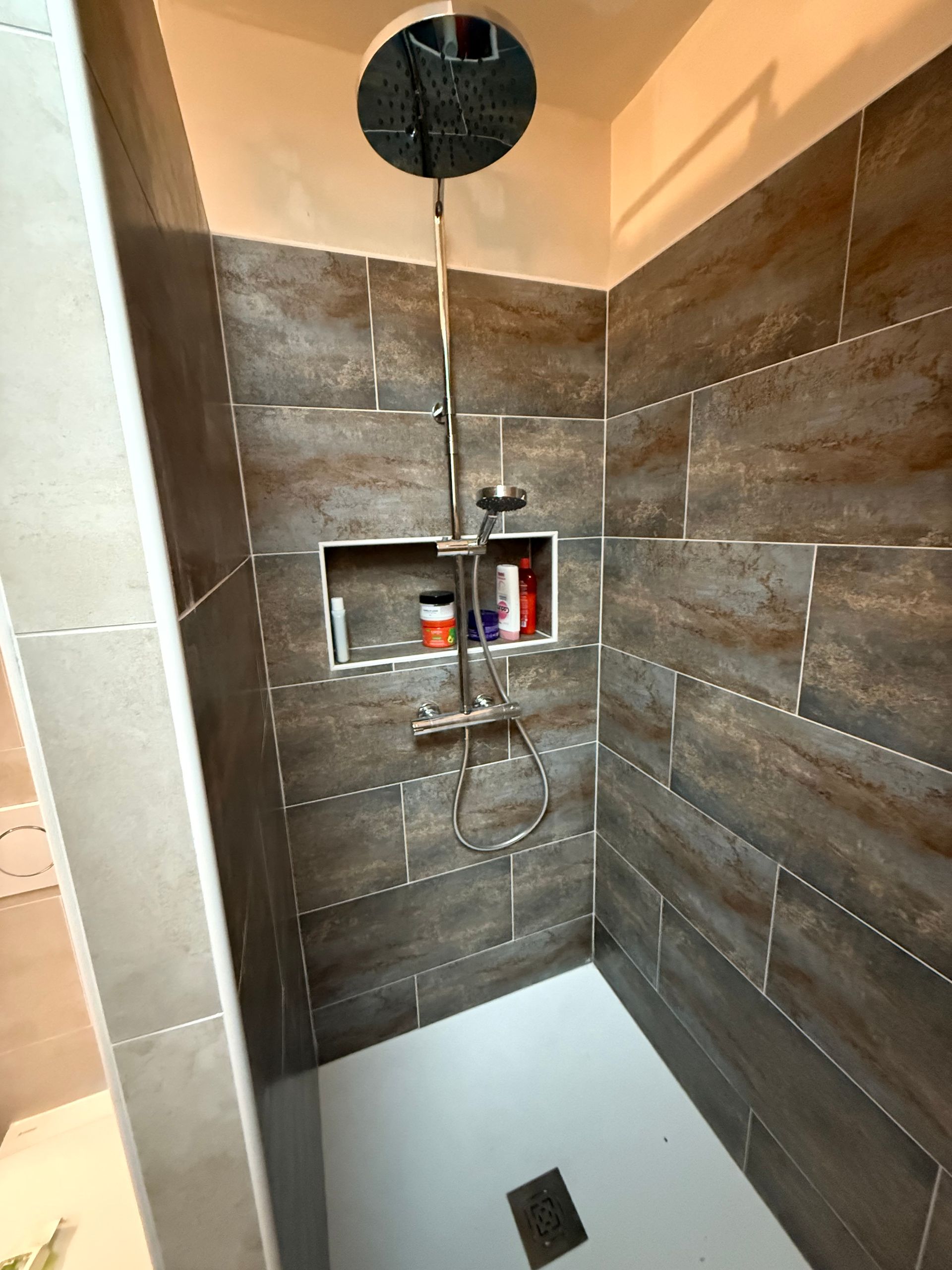 Une douche avec des murs carrelés.