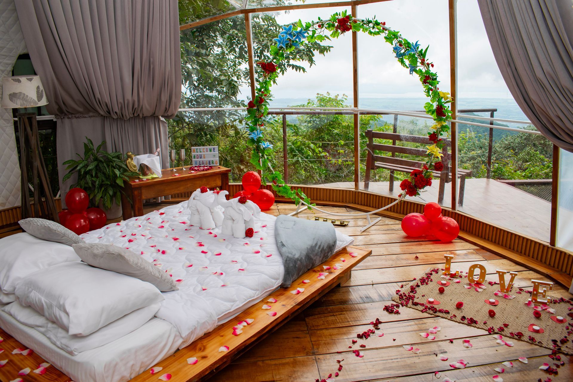 A bedroom with a bed covered in rose petals and balloons.