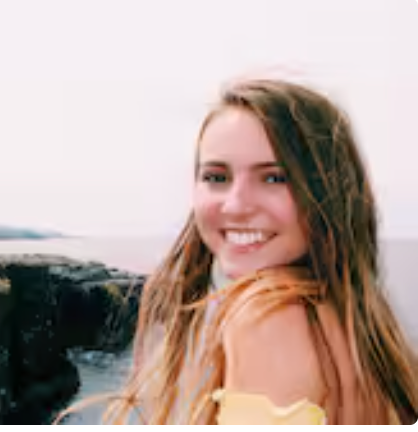 A woman is smiling for the camera while standing on a beach.