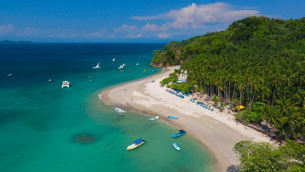 An aerial view of a tropical beach with boats in the water.