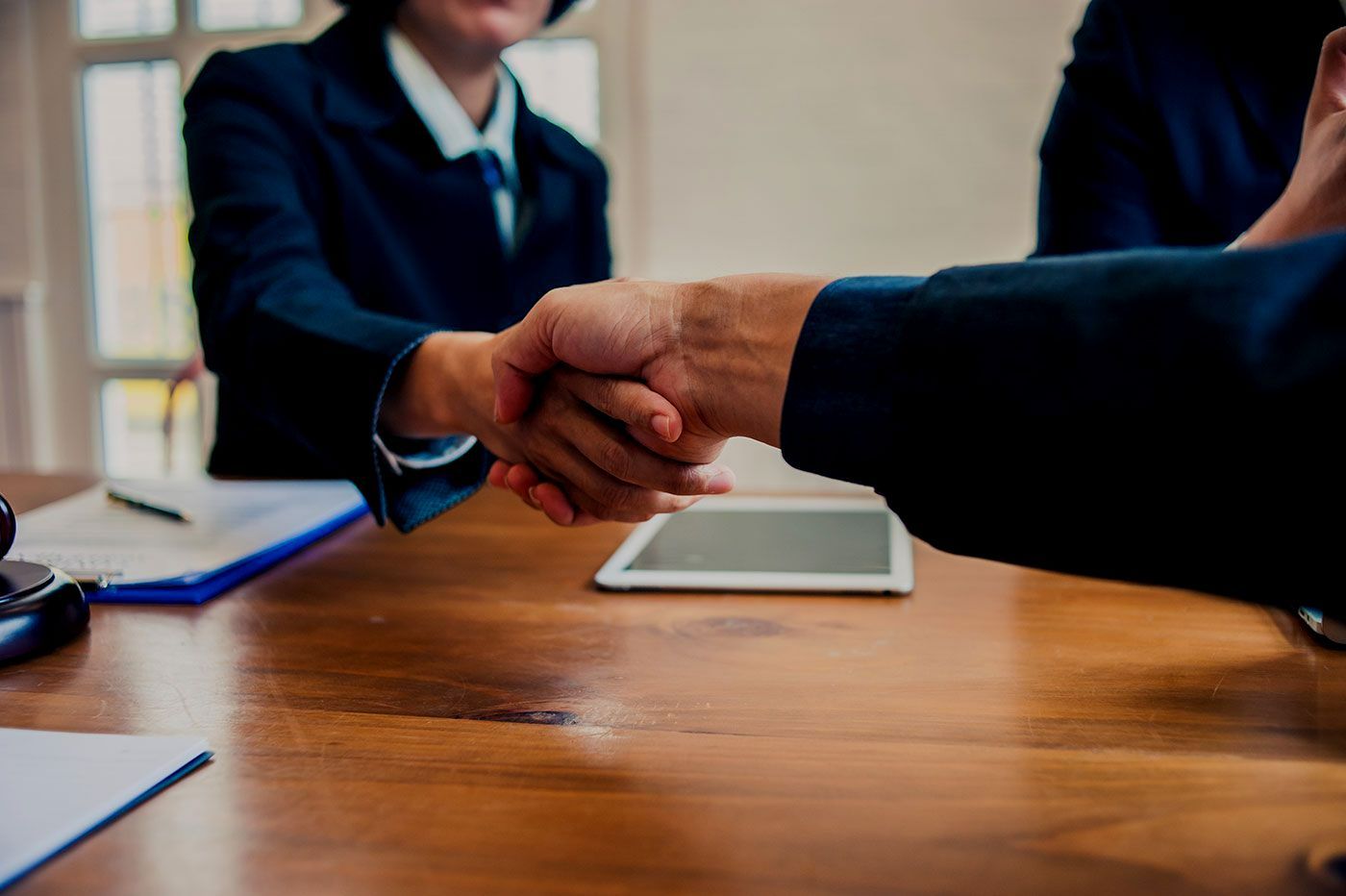 Un homme et une femme qui se serrent la main autour d'un bureau