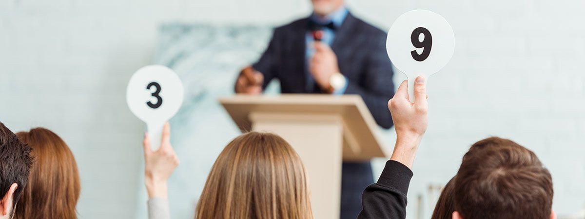 Personnes qui lèvent une plaque avec des numéros pendant une vente aux enchères