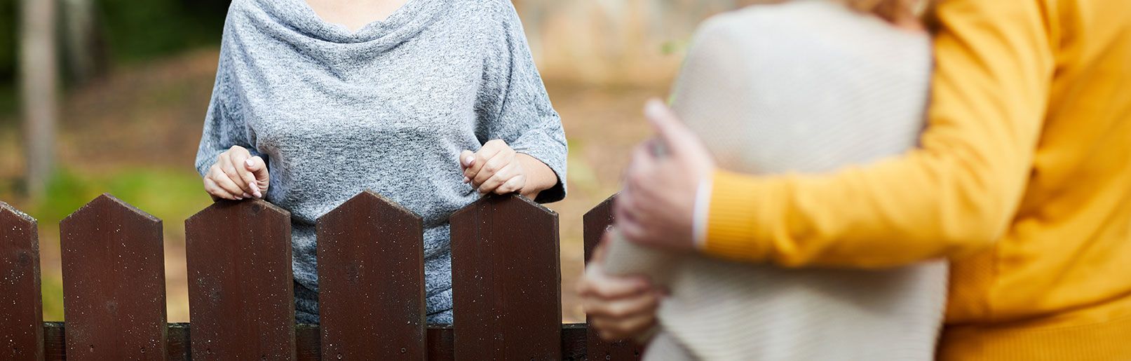 Voisins qui se parlent chacun du côté d’une barrière
