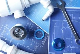 Outils et pièces de plomberie sur des plans, en bleu et blanc.