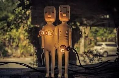 Dos enchufes eléctricos iluminados, uno al lado del otro, sobre una superficie oscura al aire libre por la noche.