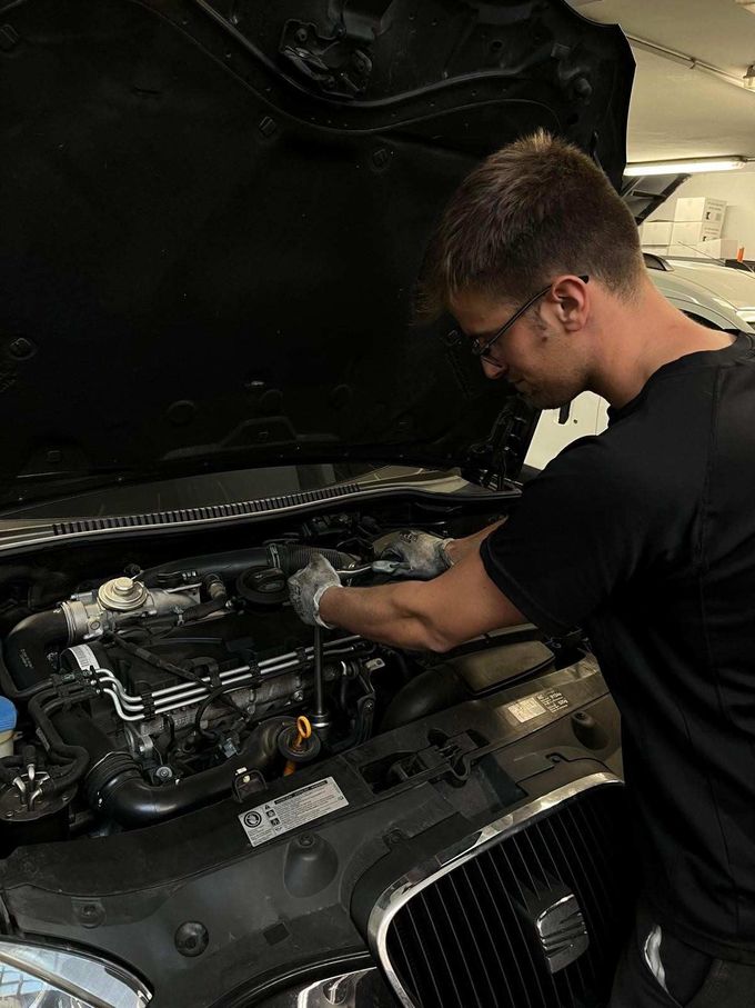 Un cliente y un mecánico se dan la mano dentro de un taller después de que le hayan hecho la revisión al coche.
