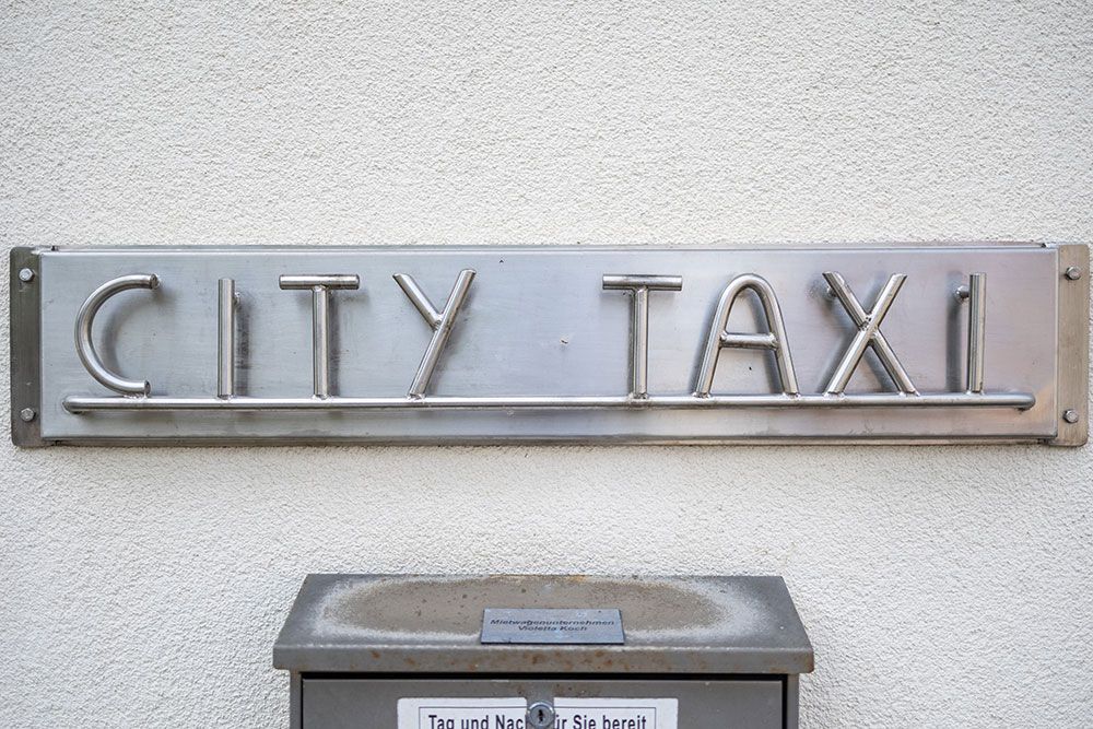 Ein Schild an einer Wand mit der Aufschrift „Stadttaxi“