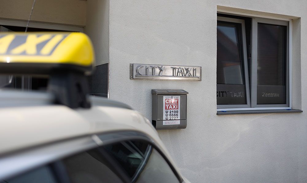 Ein Taxi steht vor einem Gebäude mit der Aufschrift „City Taxi“