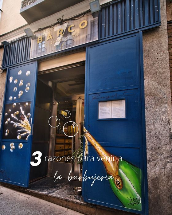 Fachada azul con puertas abiertas y un letrero que dice “MARCO”, con texto en español superpuesto en la parte inferior.
