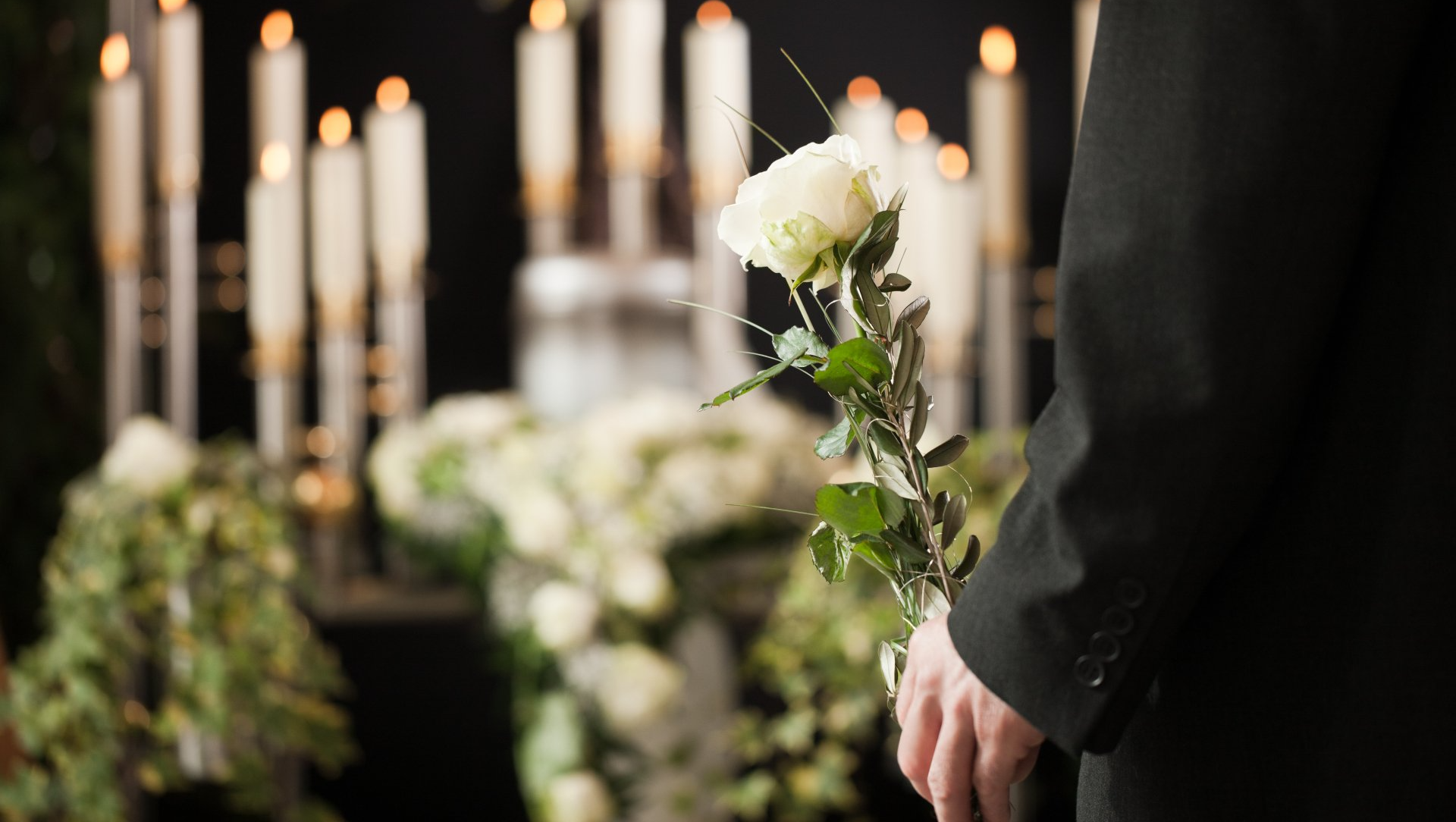 Homme qui tient une rose blanche devant cercueil
