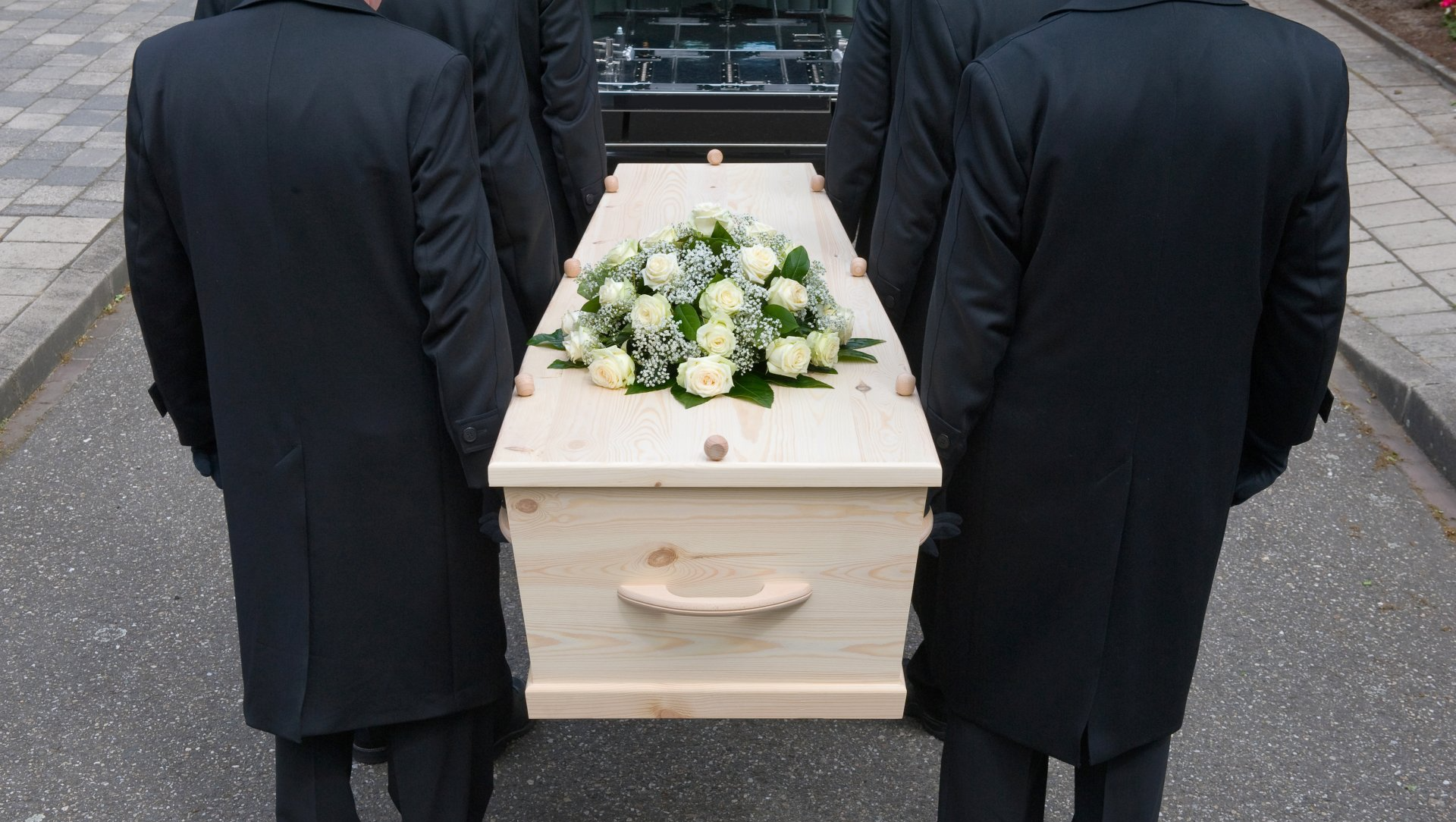 4 porteurs transportant un cercueil fleuri