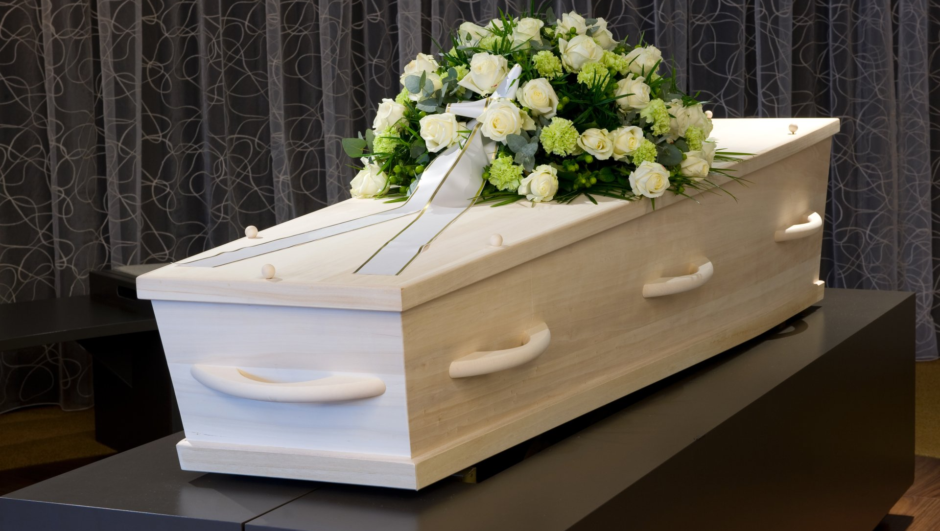 Cercueil en bois blanc avec gerbe de fleurs blanches
