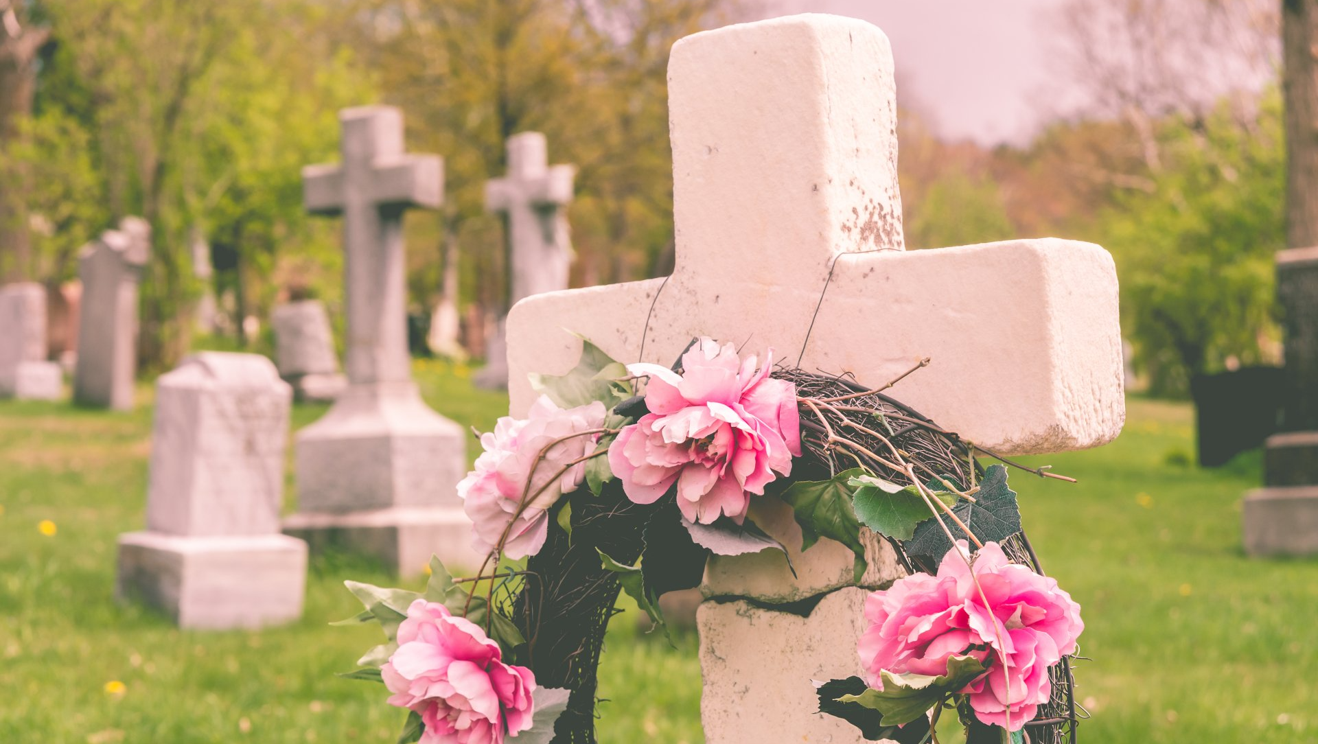Cimetière avec croix décorée d'une couronne de fleurs