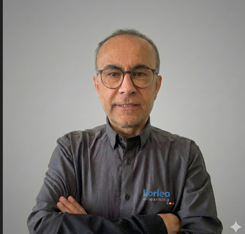 Un homme portant des lunettes et une chemise grise avec le logo « Vorlea Learning », les bras croisés.