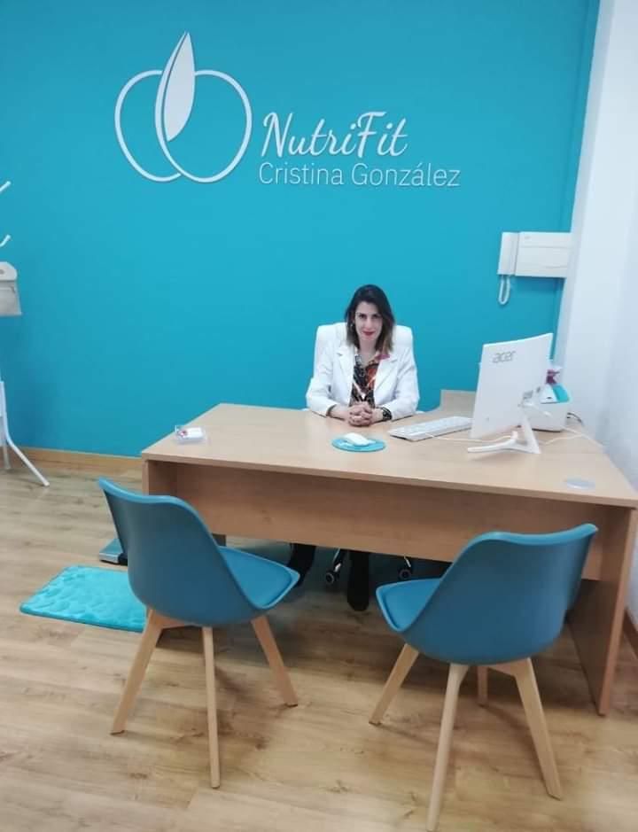 Mujer en escritorio en oficina; pared turquesa con logo 