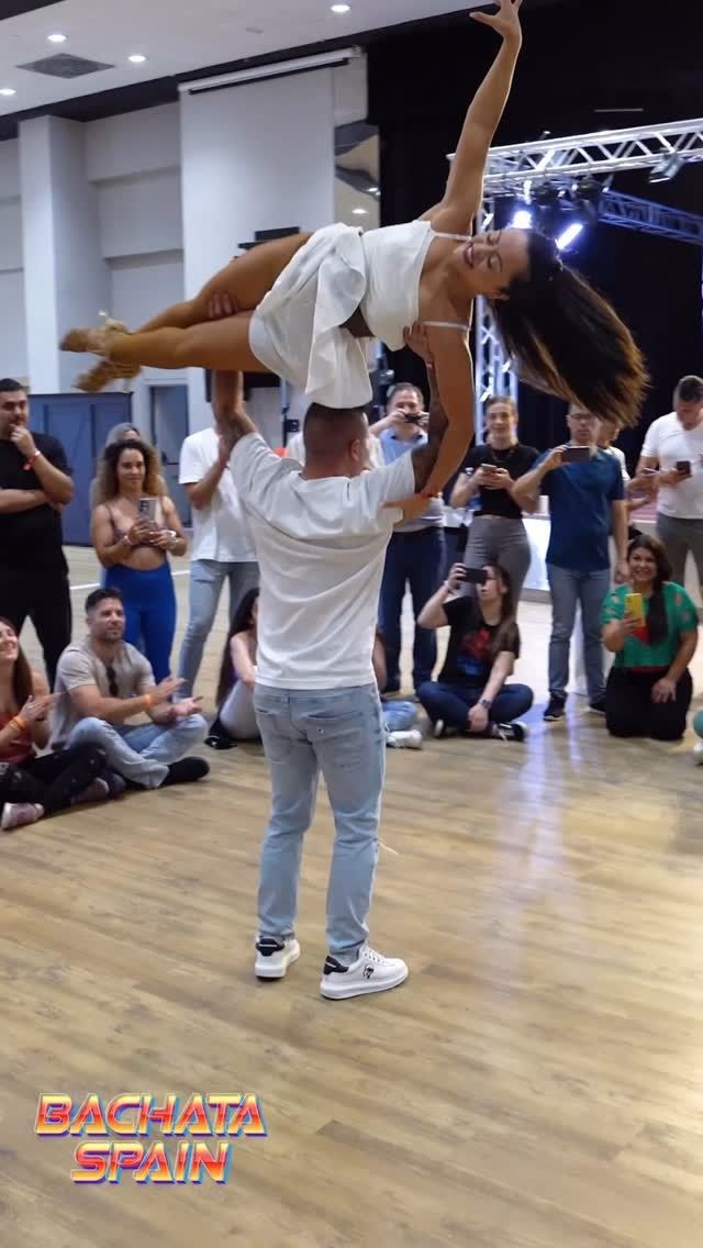 Un hombre sostiene a una mujer en el aire mientras baila en una pista de baile.
