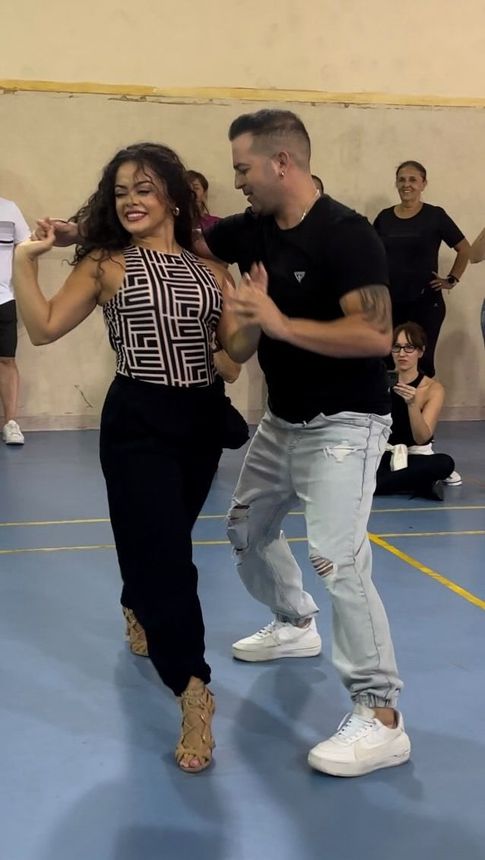 Un hombre y una mujer están bailando en un gimnasio.